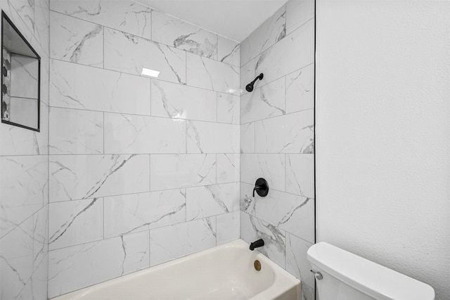 bathroom featuring toilet and tiled shower / bath