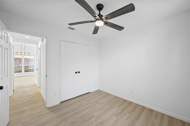 unfurnished bedroom with ceiling fan, a closet, and light wood-type flooring