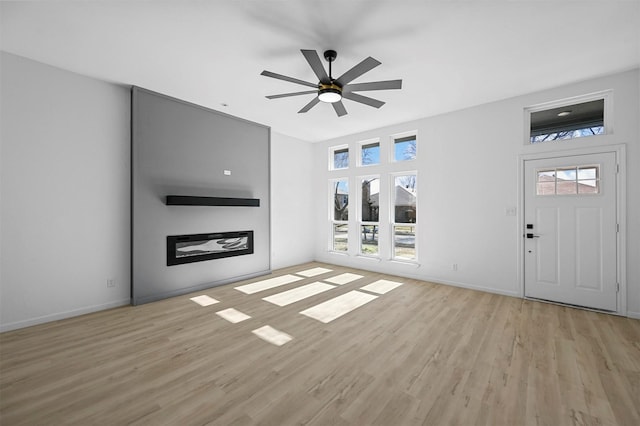 unfurnished living room featuring ceiling fan, a wealth of natural light, and light hardwood / wood-style floors