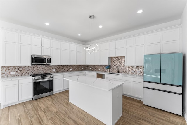 kitchen featuring appliances with stainless steel finishes, sink, hanging light fixtures, and white cabinets