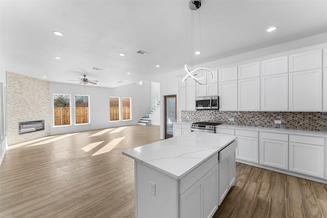 kitchen with a kitchen island, pendant lighting, white cabinetry, decorative backsplash, and stainless steel appliances