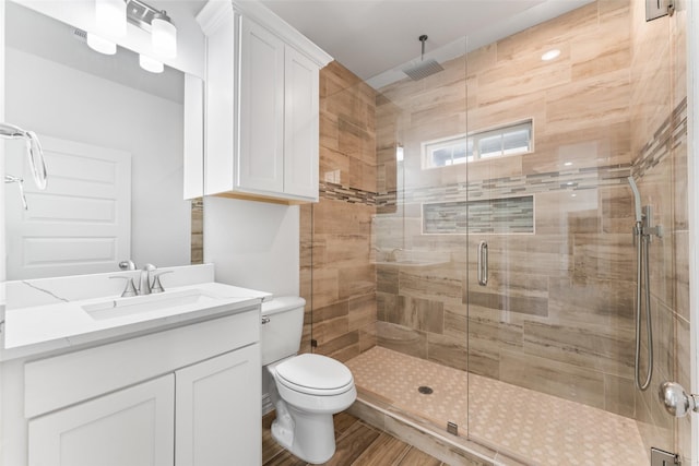 bathroom featuring vanity, toilet, a shower with shower door, and hardwood / wood-style floors