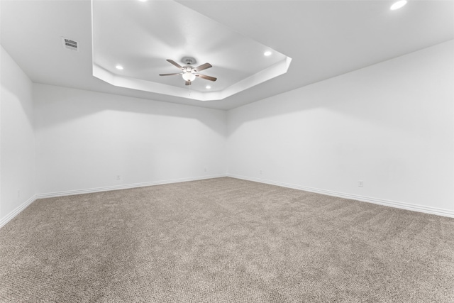 carpeted spare room featuring ceiling fan and a tray ceiling