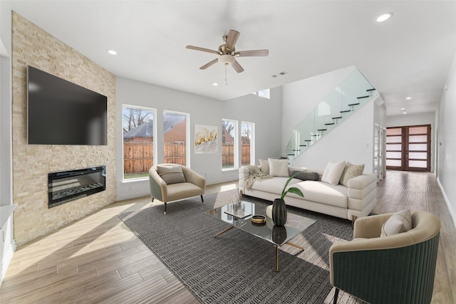 living room with ceiling fan, a fireplace, and light wood-type flooring