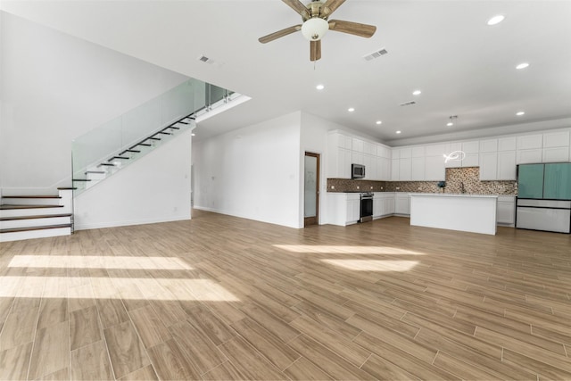 unfurnished living room featuring sink, light hardwood / wood-style flooring, and ceiling fan