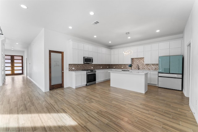 kitchen featuring stainless steel appliances, a center island, tasteful backsplash, light hardwood / wood-style floors, and white cabinets