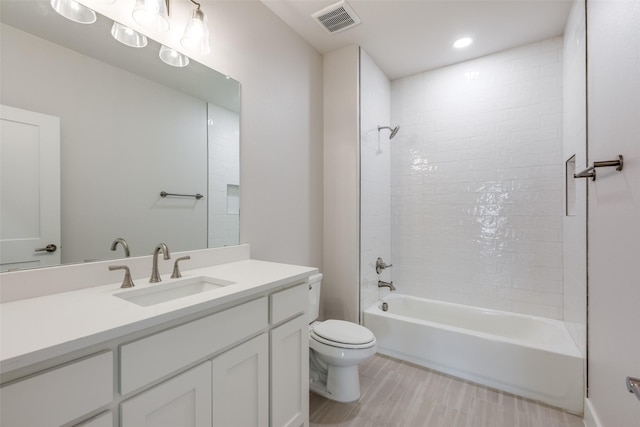 full bathroom featuring toilet, vanity, and tiled shower / bath