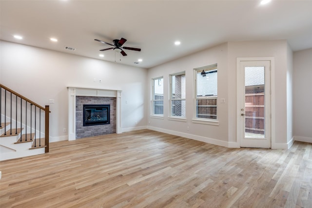 unfurnished living room featuring ceiling fan, light hardwood / wood-style flooring, and a fireplace