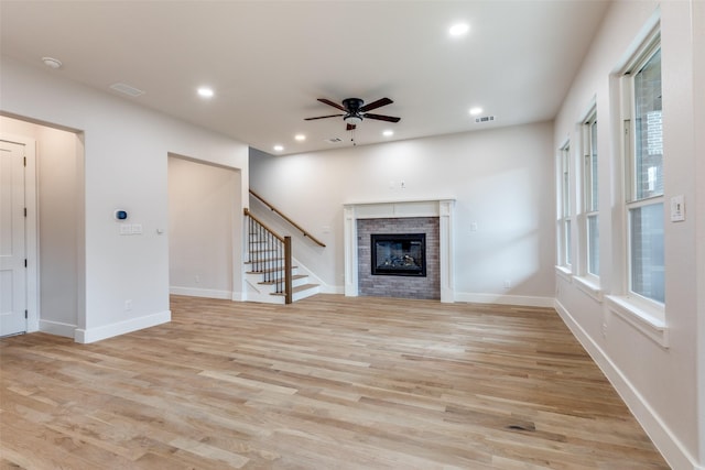 unfurnished living room with light wood-type flooring, ceiling fan, and a brick fireplace