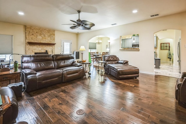 living room featuring ceiling fan with notable chandelier, dark hardwood / wood-style flooring, and a fireplace