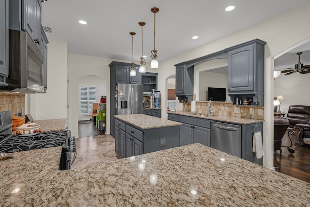 kitchen featuring ceiling fan, decorative backsplash, gray cabinetry, and stainless steel appliances