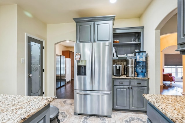 kitchen with light tile patterned floors, light stone countertops, stainless steel fridge, and gray cabinets