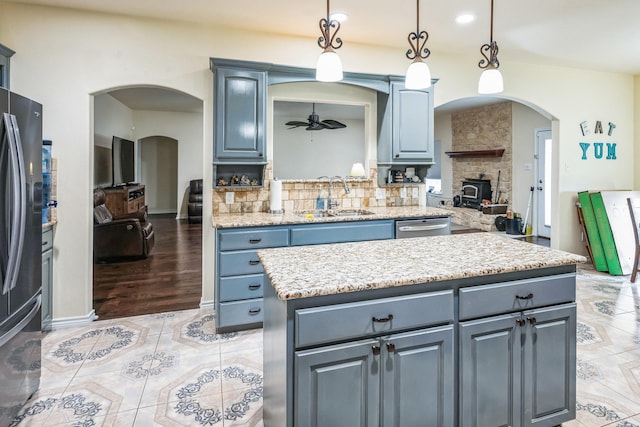 kitchen with ceiling fan, pendant lighting, a kitchen island, decorative backsplash, and sink