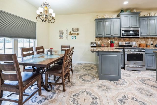 kitchen with tasteful backsplash, gray cabinets, pendant lighting, light stone countertops, and stainless steel appliances