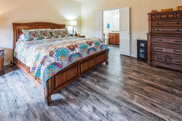 bedroom featuring connected bathroom and dark wood-type flooring