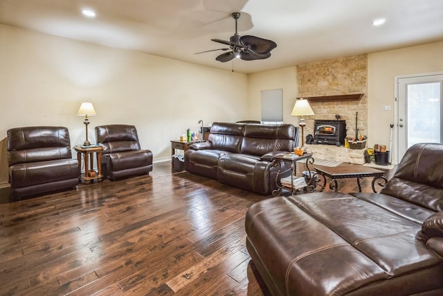 living room with ceiling fan, a wood stove, and dark hardwood / wood-style floors