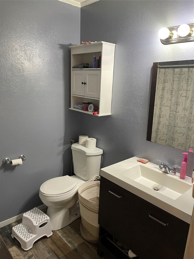 bathroom featuring toilet, crown molding, hardwood / wood-style floors, and vanity