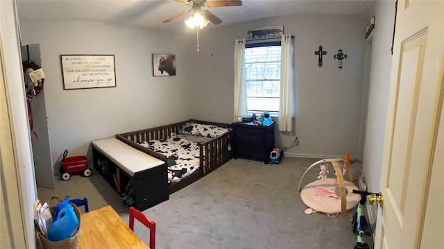 carpeted bedroom featuring ceiling fan and a nursery area