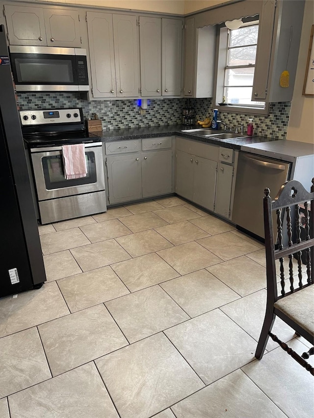 kitchen with tasteful backsplash, sink, gray cabinetry, and stainless steel appliances