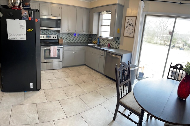 kitchen featuring stainless steel appliances, gray cabinetry, tasteful backsplash, light tile patterned flooring, and sink