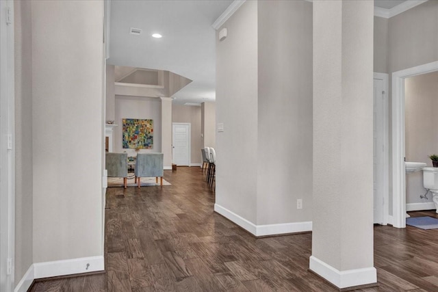 hallway featuring dark wood-type flooring, ornamental molding, and ornate columns