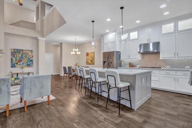 kitchen featuring decorative light fixtures, a kitchen breakfast bar, white cabinets, and a center island with sink