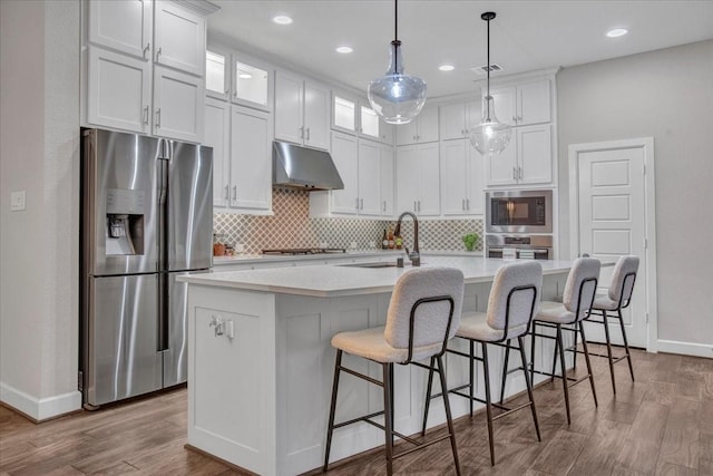 kitchen with white cabinets, appliances with stainless steel finishes, sink, and an island with sink