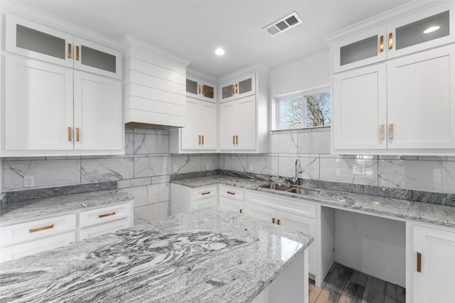 kitchen featuring light stone countertops, sink, and white cabinets