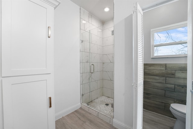 bathroom with hardwood / wood-style flooring, a shower with door, and toilet