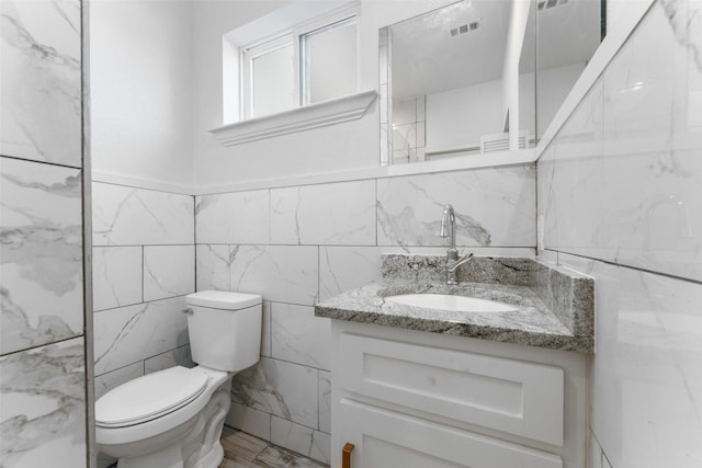 bathroom featuring vanity, tile walls, and toilet