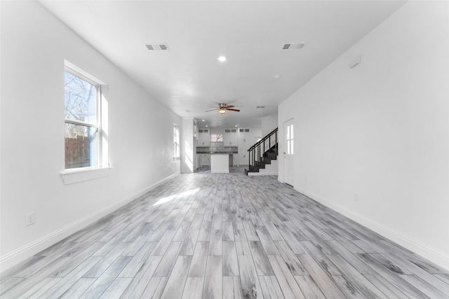 unfurnished living room featuring ceiling fan and light wood-type flooring