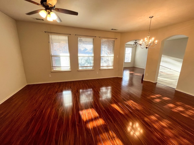 empty room with ceiling fan with notable chandelier and dark hardwood / wood-style flooring