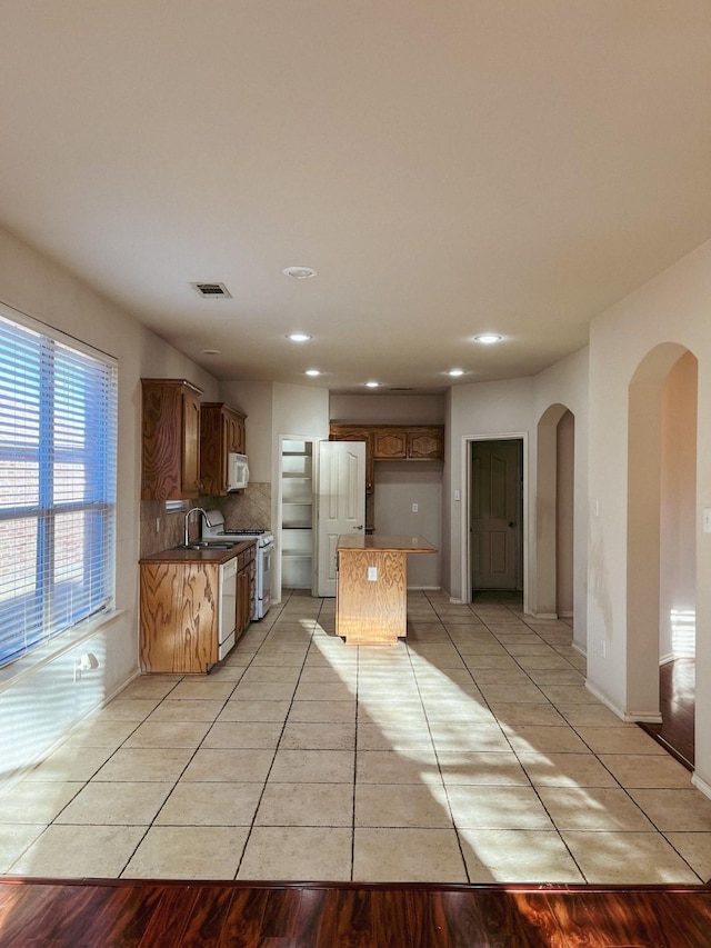 kitchen with light tile patterned floors, backsplash, and white appliances