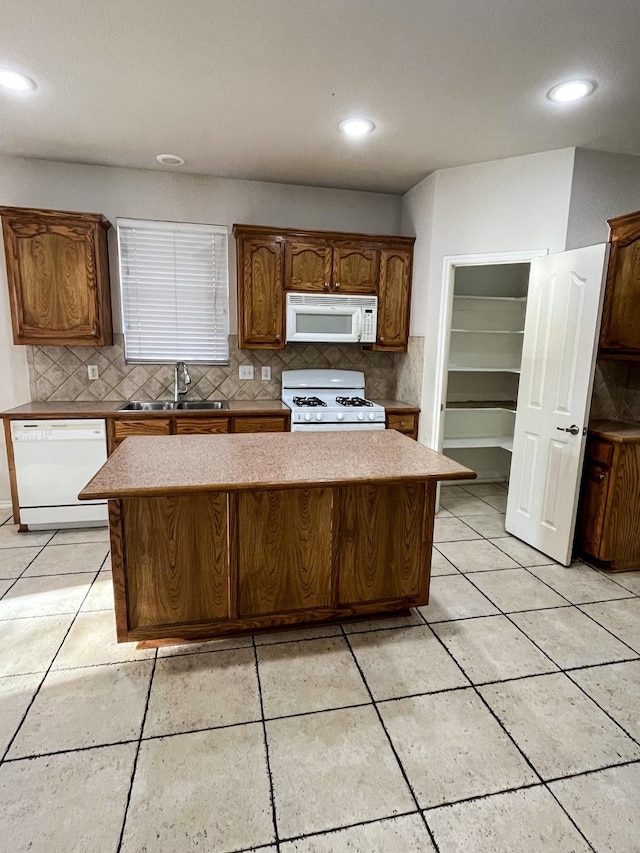 kitchen with a kitchen island, sink, backsplash, and white appliances