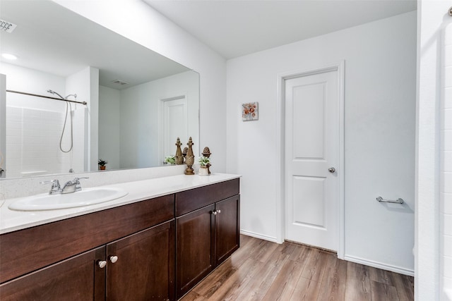 bathroom featuring walk in shower, vanity, and wood-type flooring