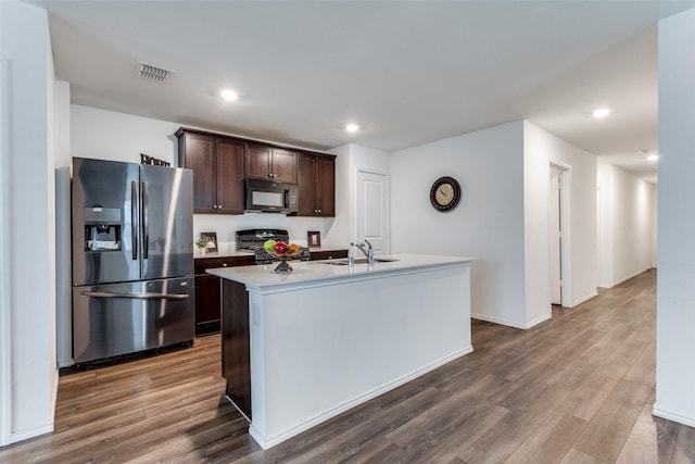 kitchen featuring sink, stainless steel fridge, range, and an island with sink