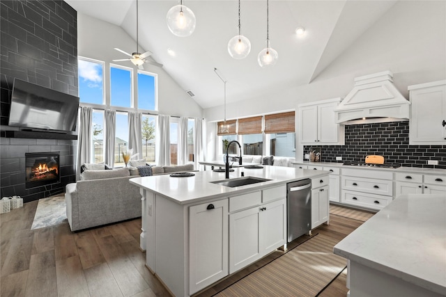 kitchen with high vaulted ceiling, a kitchen island with sink, sink, and premium range hood