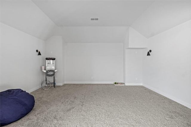 additional living space featuring vaulted ceiling and carpet flooring