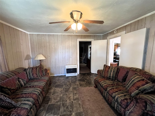 living room with heating unit, ceiling fan, wood walls, and ornamental molding