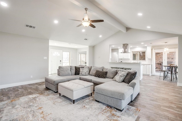 living room featuring ceiling fan with notable chandelier and lofted ceiling with beams