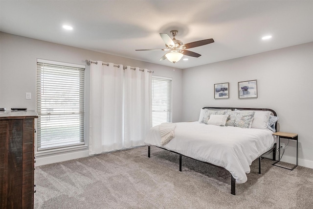 bedroom featuring ceiling fan, multiple windows, and light carpet