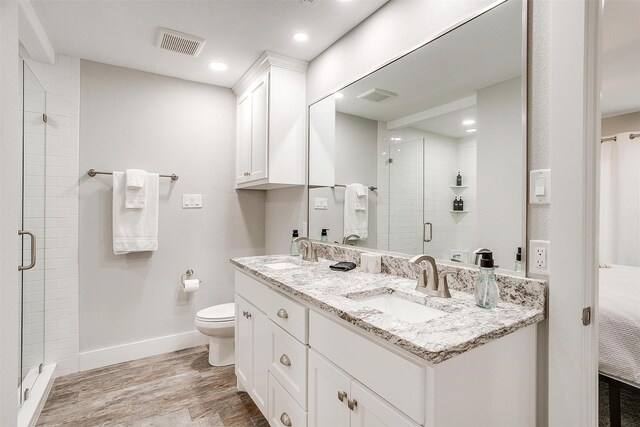 bathroom featuring toilet, a shower with shower door, hardwood / wood-style flooring, and vanity