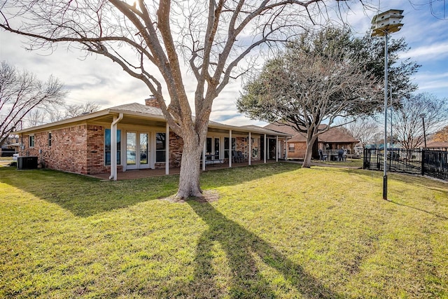 view of yard with central AC and french doors