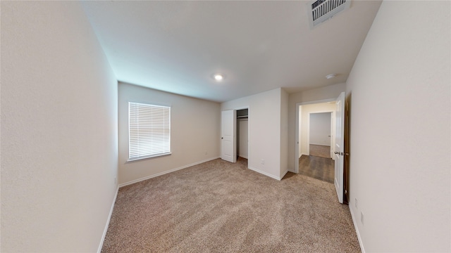 unfurnished bedroom with light colored carpet and a closet