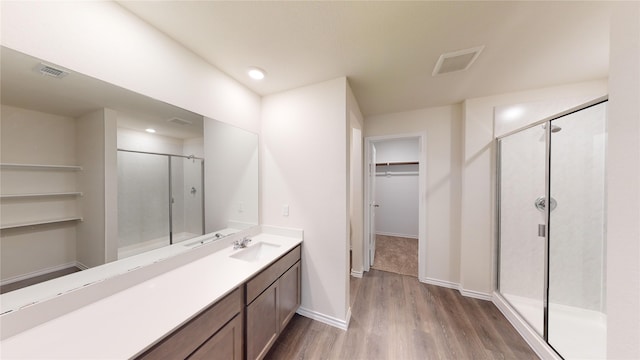 bathroom with wood-type flooring, a shower with door, and vanity