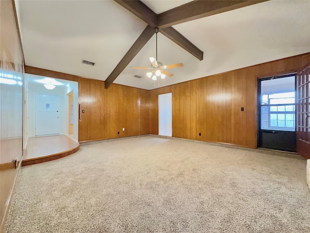 interior space with beam ceiling, ceiling fan, wooden walls, and carpet floors