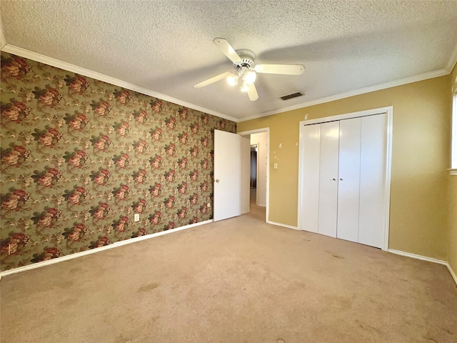 unfurnished bedroom with ceiling fan, a closet, carpet, and crown molding