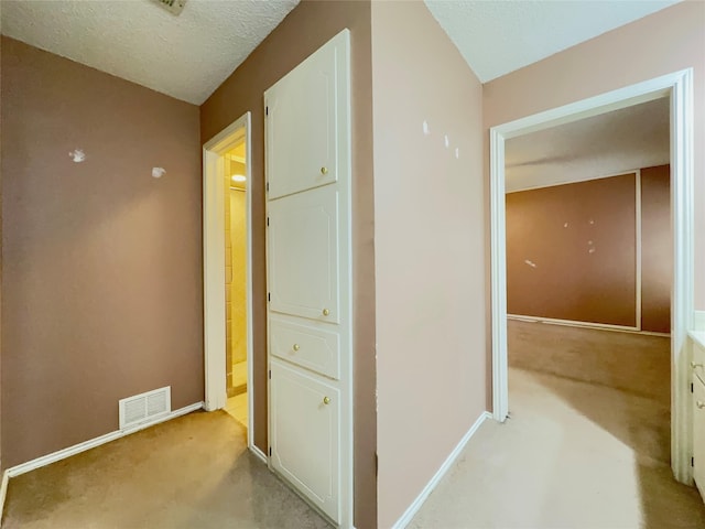 hallway featuring a textured ceiling and light carpet