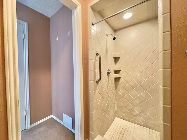 bathroom featuring a textured ceiling and tiled shower