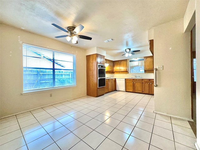 kitchen with light tile patterned floors, white dishwasher, double wall oven, and sink